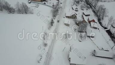 在喀尔巴阡村的冬季公路上行驶的一辆汽车上快速飞行。 鸟`雪覆盖的房子的视野。 农村